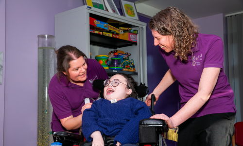 Two members of staff in purple polo tops with service user in wheelchair at Chailey Clinical Services
