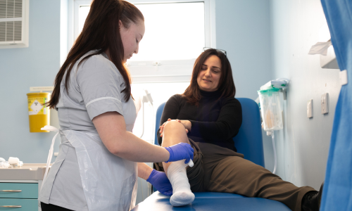 Member of staff wrapping a leg wound on a patient